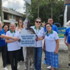 Pessoas posam para foto perto de um toten educativo
