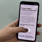 Pessoa segura celular que na tela tem informações sobre processo seletivo Join.Cubo