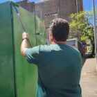 Homem de costas para a câmara segura cabo longo e aplica tinta verde com um rolo