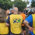 Homem de camisa preta fala para dezenas de pessoas que o ouvem dispostas em círculo