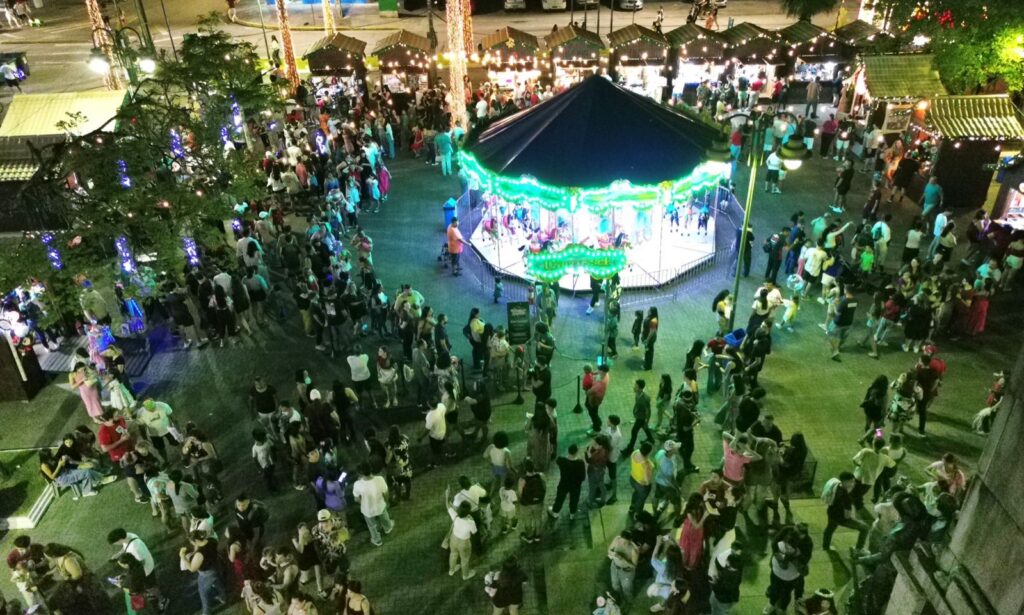 Imagem aérea mostra carrossel iluminado com centenas de pessoas ao redor