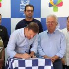 Prefeito assina documento observado por outras pessoas