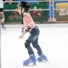Menina com capacete, joelheira e patins sorri enquanto patina em Joinville