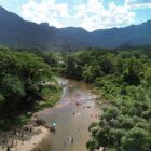 Imagem aérea mostra rio com grande mata ciliar e montanhas ao fundo
