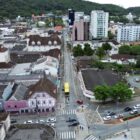 Imagem aérea da rua nove de março mostra imóveis, ônibus e outros veículos