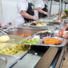Buffet com diferentes tipos de comida e bandeja de inox com feijão, arroz, salada e carne