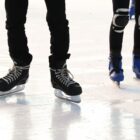 Dois pares de pés com patins na pista de gelo