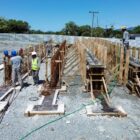 Imagem mostra canteiro de obras com concretagem de quatro estacas e dois funcionários trabalhando