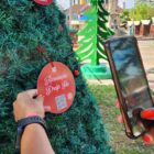 Mão de mulher segura celular para escanear QR Code de enfeite de árvore de natal