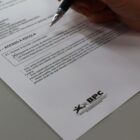 Imagem mostra mão com caneta preenchendo questionário em folha branca sobre mesa