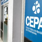 Mulher olha celular em frente a sede do Cepat