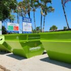 Três grandes caçambas de cor verde em área descoberta