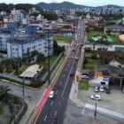 Imagem aérea mostra rua com asfaltado e sinalização renovados, com imóveis e ruas laterais no entorno