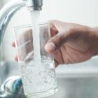 mão de homem segura copo embaixo de torneira enchendo de água