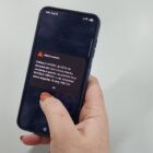 Mão segura celular que mostra alerta severo da Defesa Civil