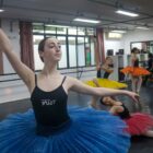 Quatro bailarinas, com figurino, ensaiam ballet clássico em sala de aula