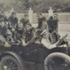 Foto antiga mostra pessoas fantasiadas desfilando em um carro antigo