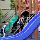 Crianças uniformizadas brincam em playground em escola
