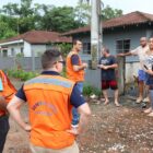 Técnicos da Defesa Civil uniformizados conversam com moradores em rua