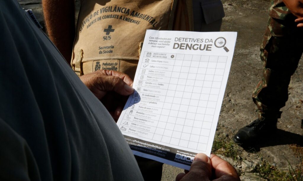 Homem segura papel com informações sobre dengue