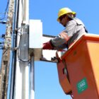 Homem com uniforme e capacete trabalha em posto de iluminação elétrica