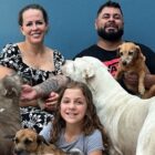 Família, com pai, mãe e filha seguram cachorros