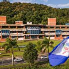 Fachada da sede da Prefeitura de Joinville com uma bandeira da cidade a frente