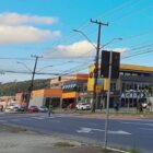 Avenida, com quatro pistas, canteiro central, carros trafegando e pedestre atravessando em faixa