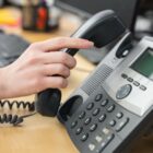 Mão de mulher pega telefone em mesa