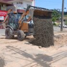 Máquina despeja mistura de terra e brita em local de obra na rua Tenente Antônio João