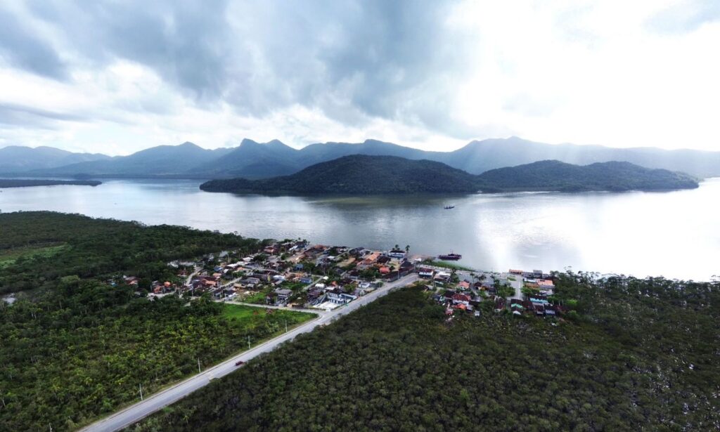 Imagem aérea da Vigorelli mostra a Baía Babitonga, morros, área de vegetação e casas