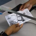 Mãos seguram o carnê da Coleta de Lixo