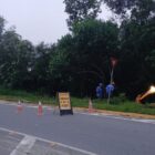 Imagem mostra máquina trabalhando às margens de rua, em área de vegetação