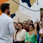 Homem em pé, de frente para plateia sentada