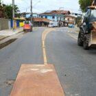 Rua de asfalto com sinalização viária, homem e equipamentos de manutenção