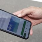 Mão masculina segura celular com o Passebus Mobile na tela