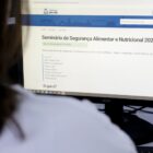 Mulher olhando para tela de computador na página da prefeitura com informações do Seminário de Segurança Alimentar e Nutricional