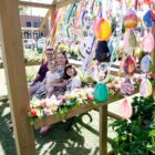 Família sentada em banco com ovos de páscoa pintados enfeitando o ambiente