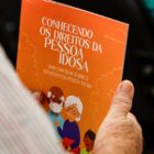 Idoso segura cartilha com informações do Estatuto do Idoso