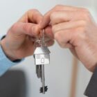 Mãos de duas pessoas diferentes seguram a chave de uma casa