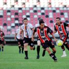 Homens uniformizados de times diferentes jogam futebol em um estádio