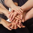 Diversas mãos femininas estão entrelaçadas