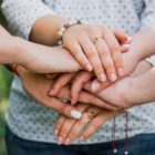 Mãos de mulheres juntas, uma em cima da outra, simbolizando união