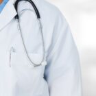 Imagem mostra pessoa não identificada usando jaleco branco com estetoscópio no ombro