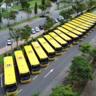 Imagem aérea mostra 18 ônibus amarelos posicionados lado a lado