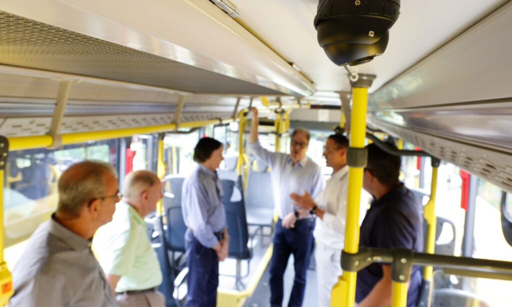 Seis homens brancos estão em pé dentro de um ônibus