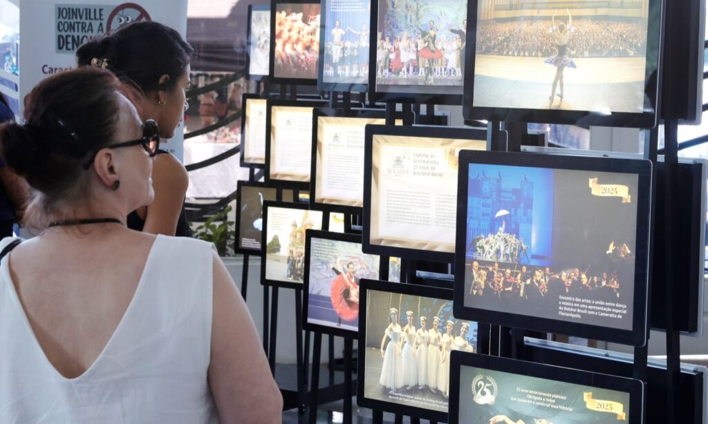 Duas mulheres observam uma exposição de quadros sobre a história do Bolshoi