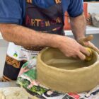 Homem não identificado manuseia uma peça de cerâmica semelhante a uma panela