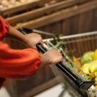 Mulher empurra carrinho de supermercado com compras