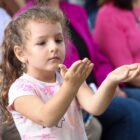 Menina estica as duas mãos para cima